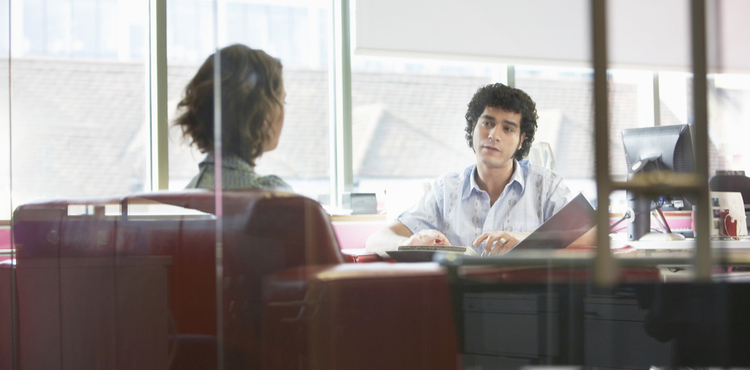 Two people meeting in an office with glass walls.