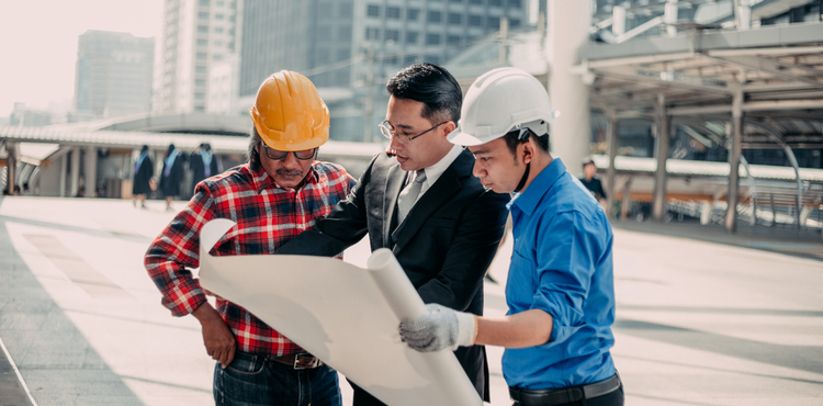 Contractors and a businessman review building plans. Contractors and a businessman review building plans.