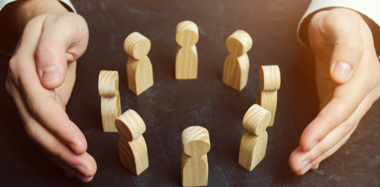 Two hands cupped around a circle of wooden figures. Two hands cupped around a circle of wooden figures.