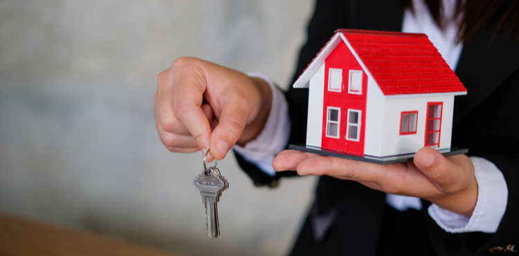 A miniature house and keys in a hand. A miniature house and keys in a hand.