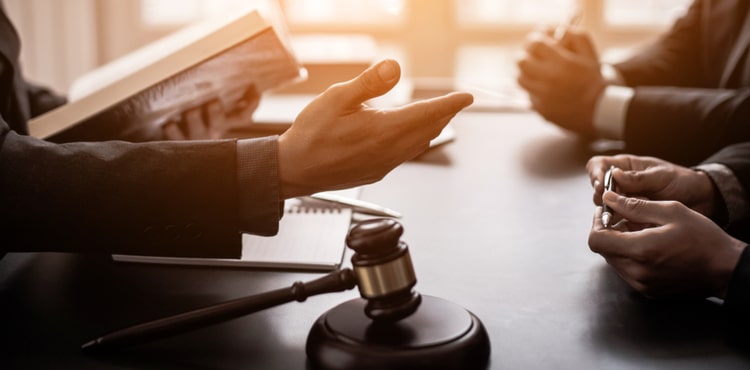 A group of lawyers consulting behind a gavel. A group of lawyers consulting behind a gavel.