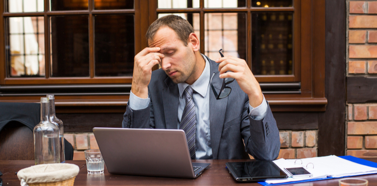 An upset man sets at a desk in front of a laptop. An upset man sets at a desk in front of a laptop.