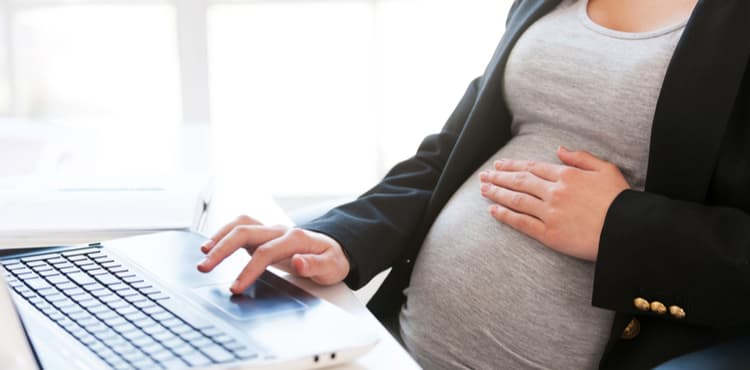 Pregnant woman at her desk. Pregnant woman at her desk.