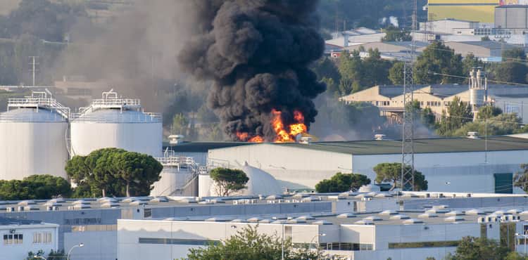 Factory burns and emits black cloud of smoke.
