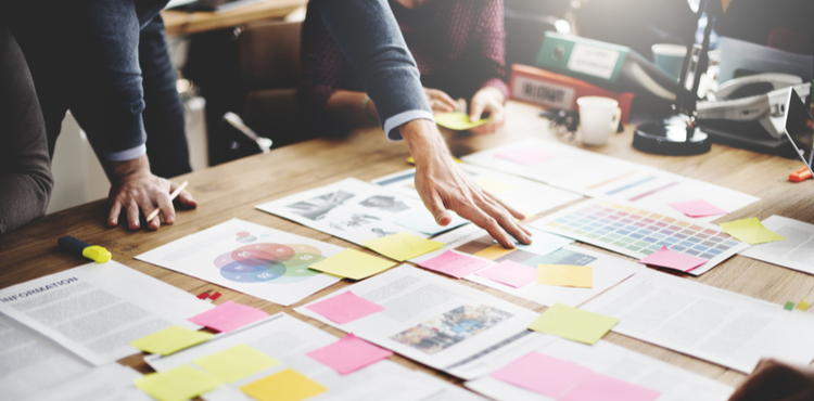 Several people pour over business plans and charts. Several people pour over business plans and charts.