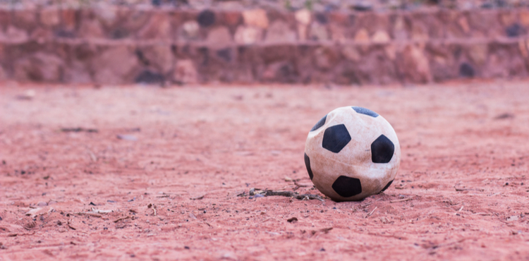 A deflated soccer ball lays on a clay field. A deflated soccer ball lays on a clay field.