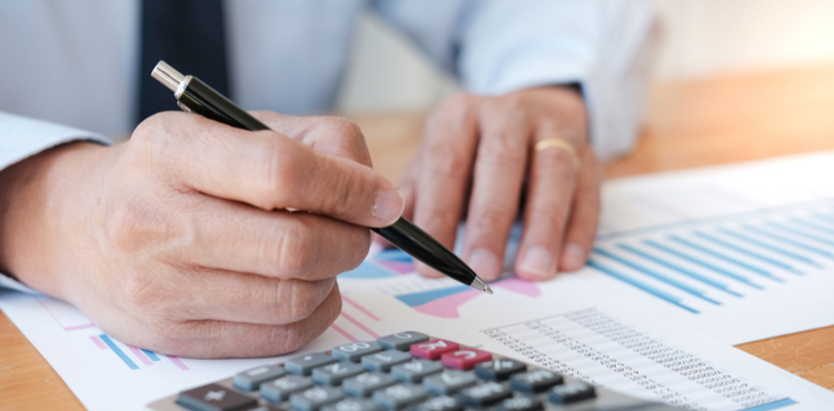 Man does calculations on a report. Man does calculations on a report.