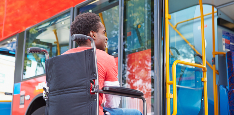 A disabled man in a wheelchair boards a bus. A disabled man in a wheelchair boards a bus.