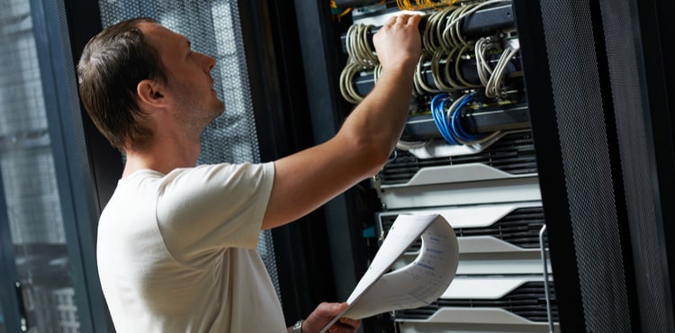 An IT technician completes a checklist in a server room. An IT technician completes a checklist in a server room.