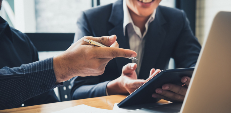 Two business men discuss information on a tablet. Two business men discuss information on a tablet.