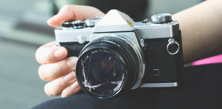 A woman holds a camera with a broken lens. A woman holds a camera with a broken lens.