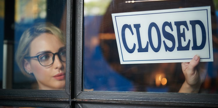 Woman puts closed sign in window of business. Woman puts closed sign in window of business.