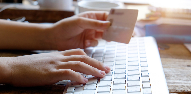 A woman enters her credit card details on a computer. A woman enters her credit card details on a computer.