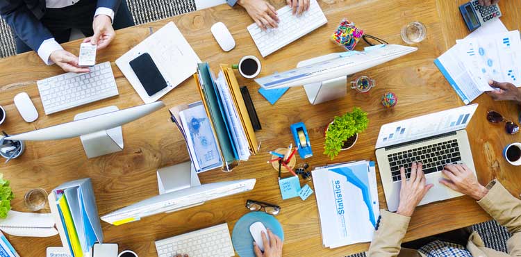 Business people using laptops at a large office table viewed from above. Business people using laptops at a large office table viewed from above.