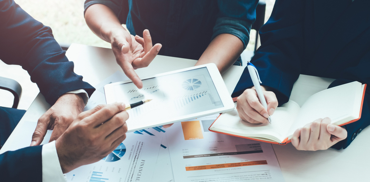 Three business people discuss analytics report and take notes. Three business people discuss analytics report and take notes.