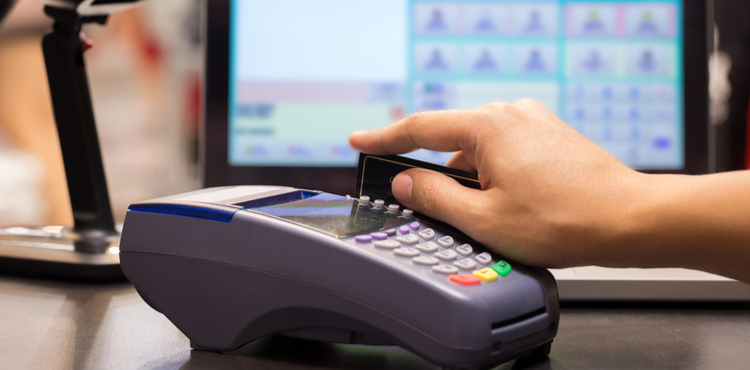 A cashier runs a credit card through a credit card machine. A cashier runs a credit card through a credit card machine.