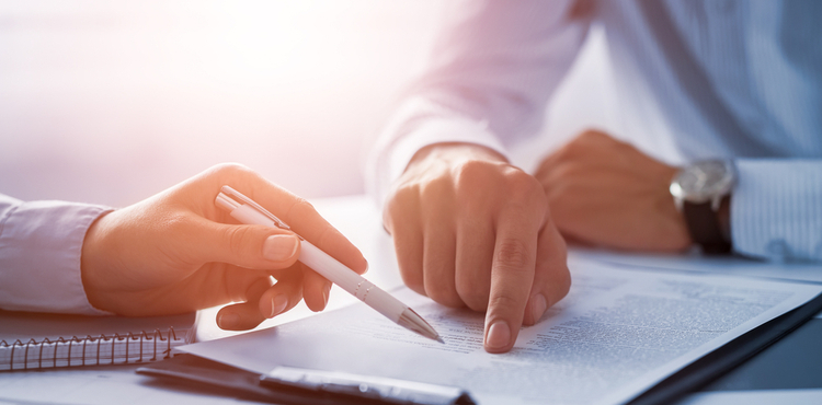 A closeup of two people reviewing a contract. A closeup of two people reviewing a contract.