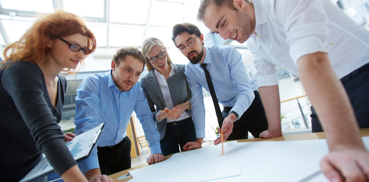 A design team examines papers on a table. A design team examines papers on a table.