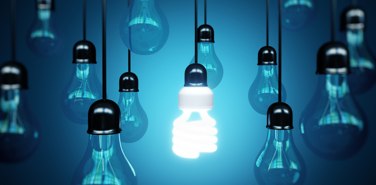 An energy efficient lightbulb hanging among regular lightbulbs. An energy efficient lightbulb hanging among regular lightbulbs.