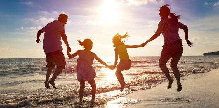 A family plays in the water on a beach at sunset. A family plays in the water on a beach at sunset.