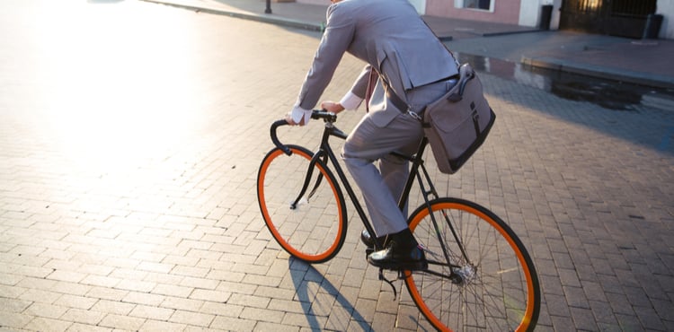 A man in a suit biking with a messenger bag. A man in a suit biking with a messenger bag.