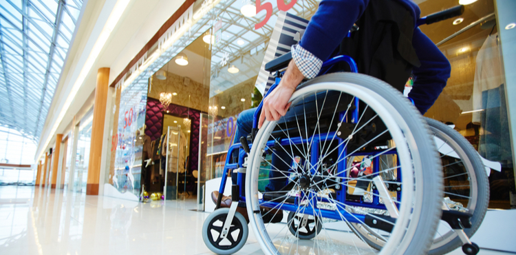 A man in a wheelchair window shops in the mall. A man in a wheelchair window shops in the mall.