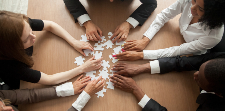 A team of people working together on a jigsaw puzzle. A team of people working together on a jigsaw puzzle.