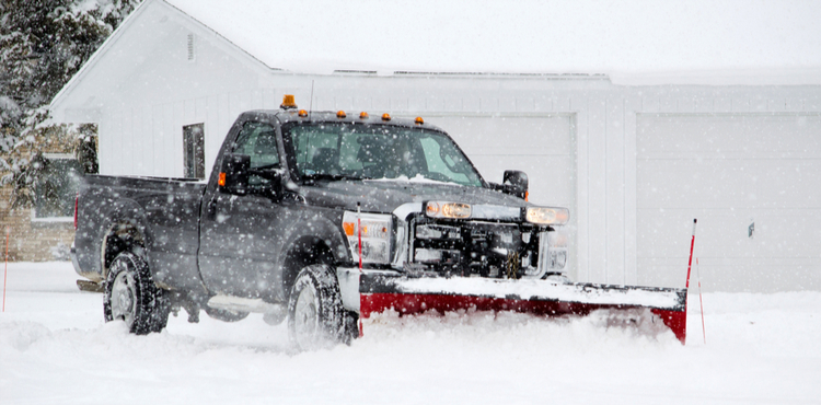 A plow truck clears a driveway in Michigan. A plow truck clears a driveway in Michigan.