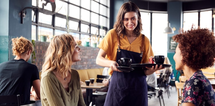 A server brings a tray of drinks to a table. A server brings a tray of drinks to a table.