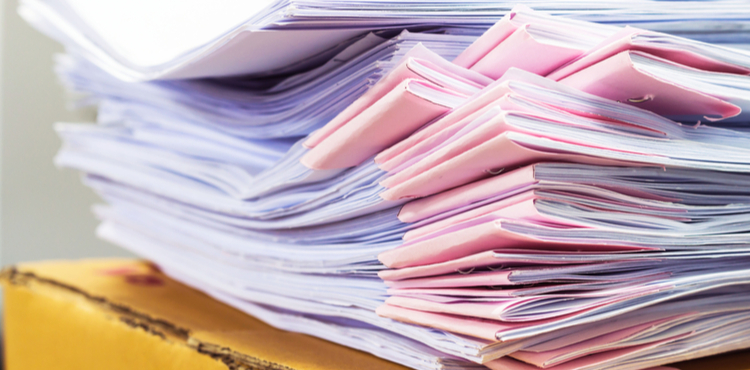 A stack of paper booklets sits on top of a cardboard box. A stack of paper booklets sits on top of a cardboard box.