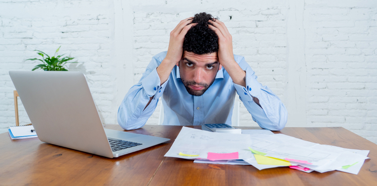A man sitting at a desk with his hands on his head. A man sitting at a desk with his hands on his head.
