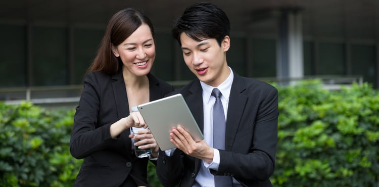 Two business people share a tablet in a park. Two business people share a tablet in a park.