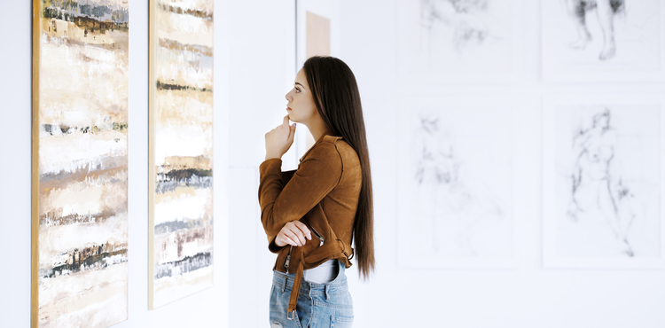 A woman contemplates paintings in an art gallery. A woman contemplates paintings in an art gallery.