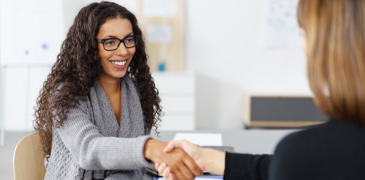 Two business women shake hands across a desk. Two business women shake hands across a desk.