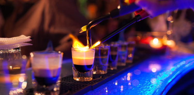 A bartender lights a flaming shot with a blow torch. A bartender lights a flaming shot with a blow torch.