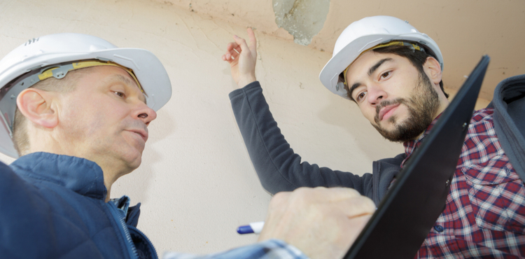 Two construction workers examine and take notes on crumbling plaster ceiling. Two construction workers examine and take notes on crumbling plaster ceiling.