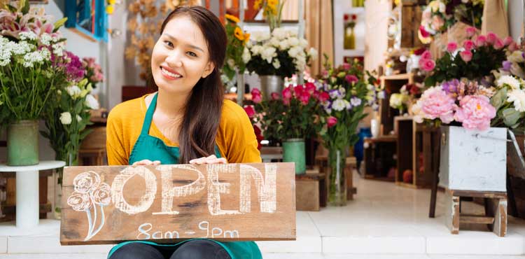 A woman holding an open sign in a flower shop. A woman holding an open sign in a flower shop.