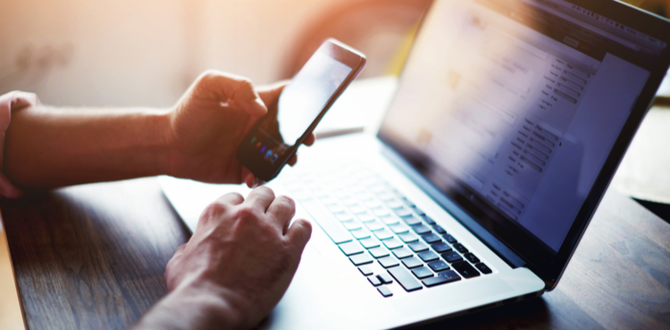 Side view of a man's hands using smart phone and laptop. Side view of a man's hands using smart phone and laptop.
