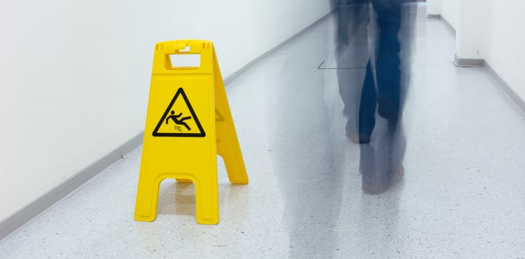 A caution wet floor sign and a man walking by. A caution wet floor sign and a man walking by.