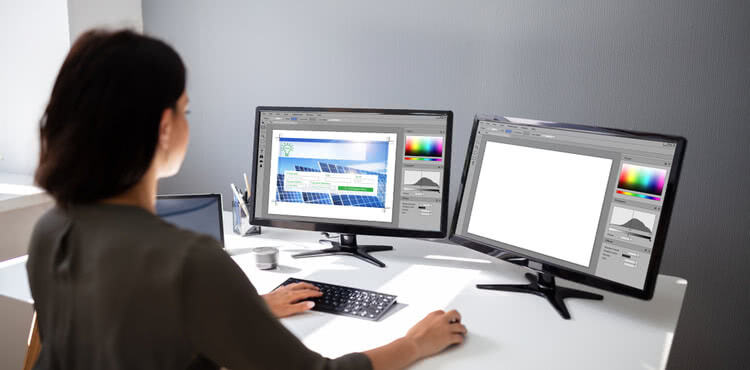 Female web designer working with two monitors
