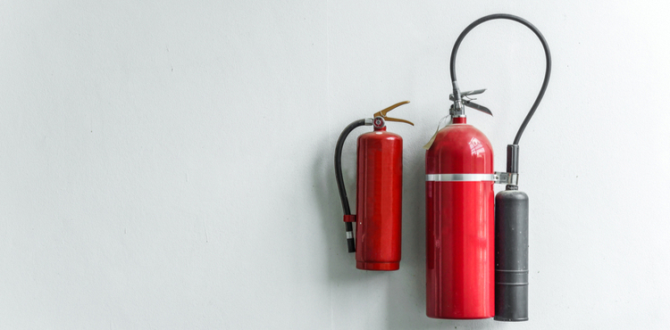 Two fire extinguishers hung on a white wall. Two fire extinguishers hung on a white wall.