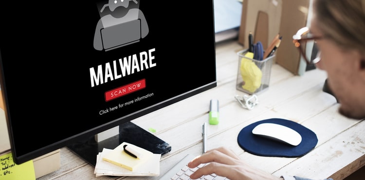 A man looking at a computer screen that says 'malware'.