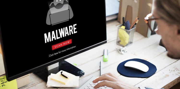A man looking at a computer screen that says 'malware'. A man looking at a computer screen that says 'malware'.