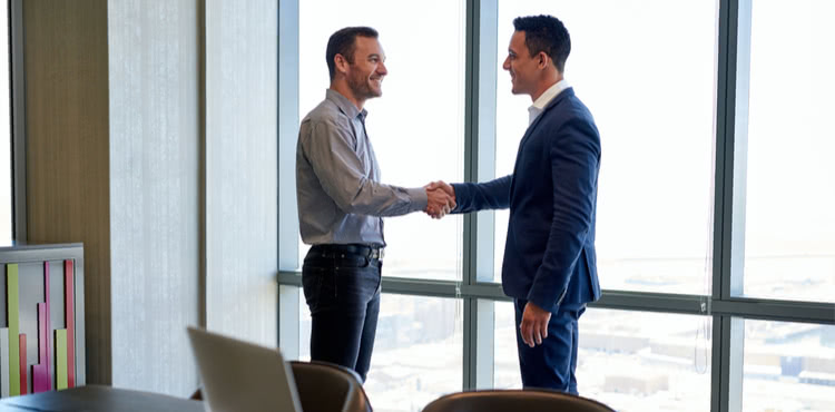 Two men shaking hands in an office Two men shaking hands in an office