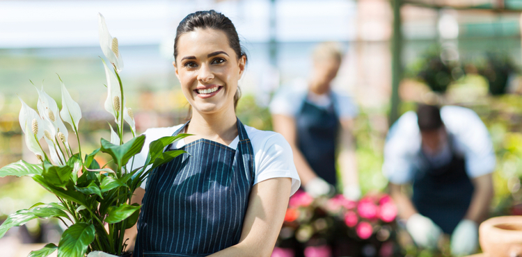 A woman wearing an apron and holding a plant. A woman wearing an apron and holding a plant.