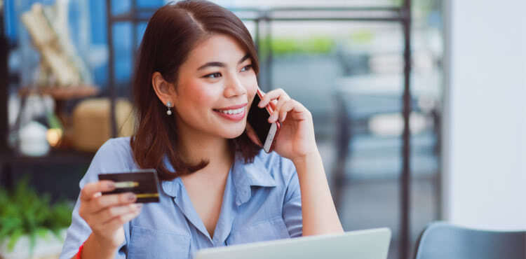 Woman holding credit card and talking on phone Woman holding credit card and talking on phone