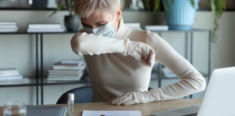 Woman in mask coughing at desk Woman in mask coughing at desk