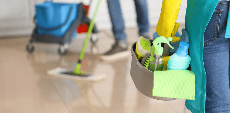 Two cleaning employees, mopping and carrying a cleaning caddy.