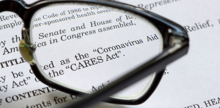 Reading glasses resting on top of a copy of the CARES COVID relief act.
