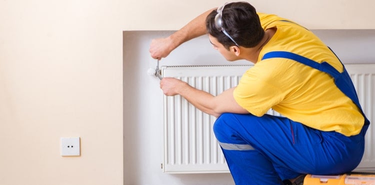 A handyman fixes a vent in a house